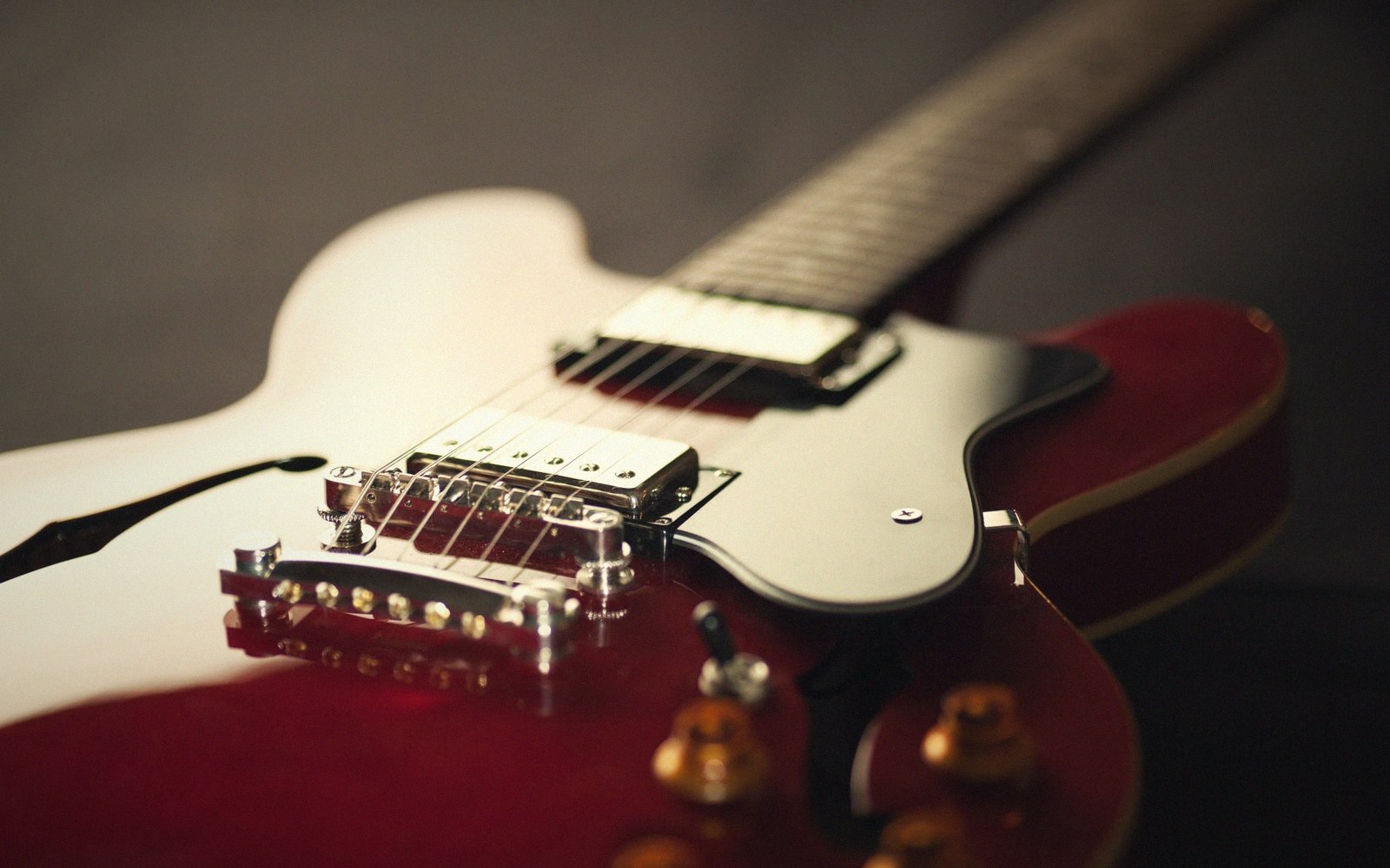 Close-up of a red electric guitar body with chrome pickups and control knobs