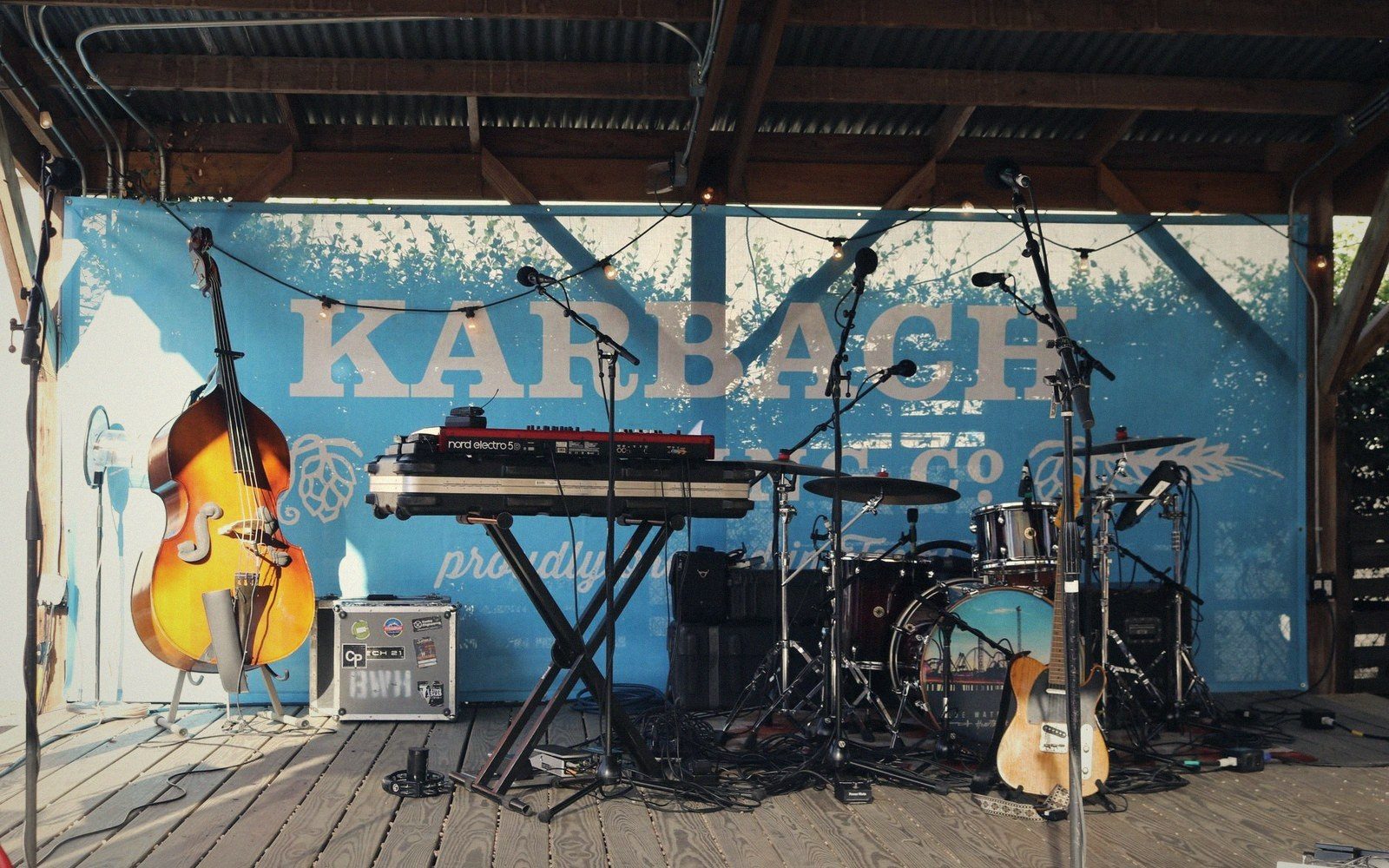 Empty stage with upright bass, keyboard, drum kit and guitar under a pavilion