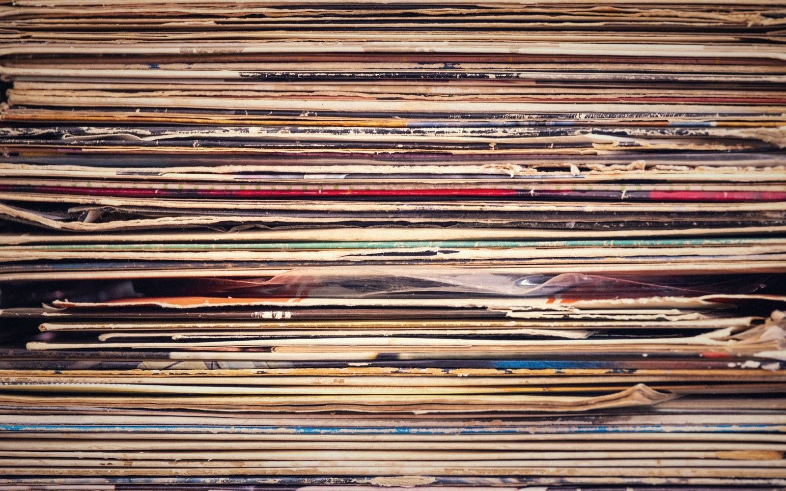 Tightly packed stack of worn vinyl record sleeves viewed from the edge