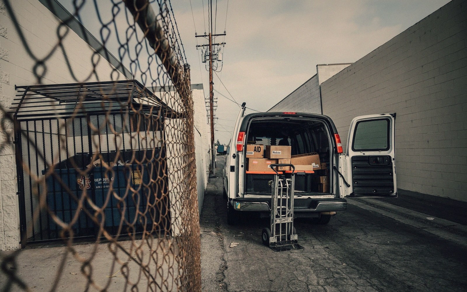 A venue load-in door in a back lane, roller shutter up, flight cases waiting