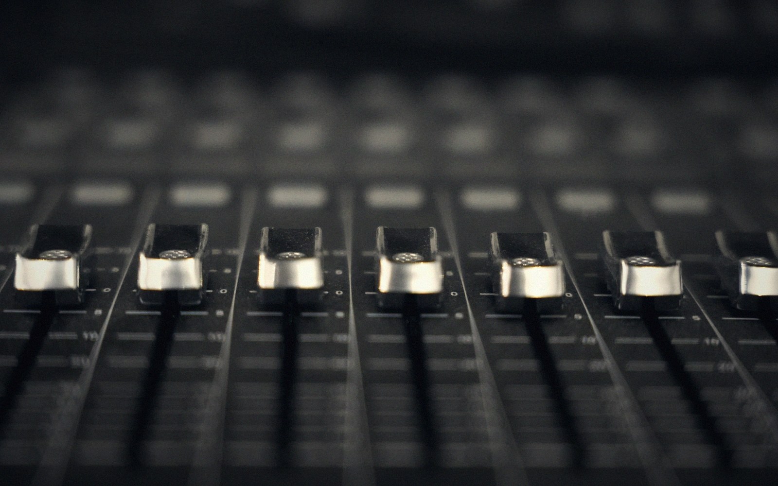 A live mixing desk mid-set, faders lit, gaffer-tape channel labels